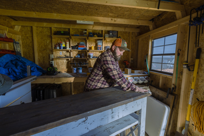 Robert Woody staining a wood table in his workshop