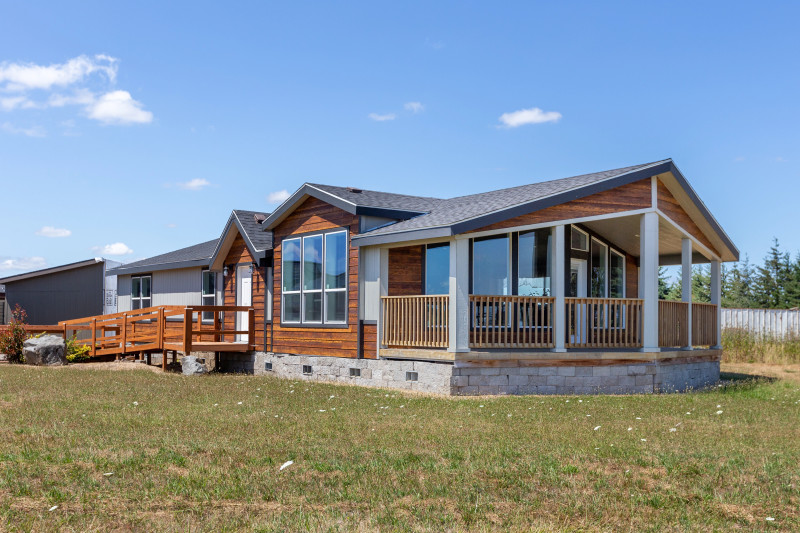 Exterior of a Clayton manufactured home with a prow front porch, wood siding and stone skirting.