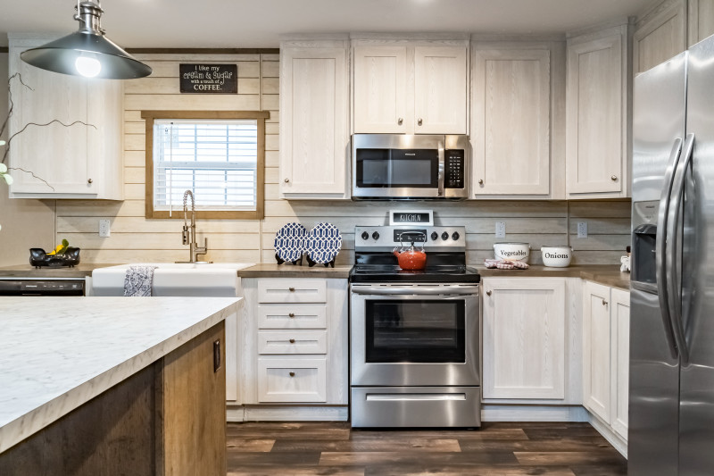 Manufactured home kitchen with white cabinetry and stainless steel appliances.