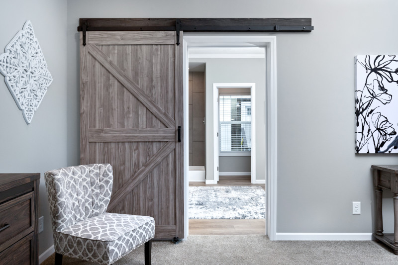 Farmhouse style barn doors in a primary bedroom that lead into a connecting bathroom of The Laney manufactured home.