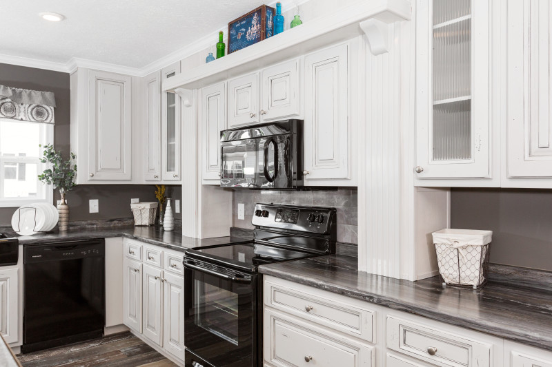 White and grey manufactured home kitchen with large cabinets.