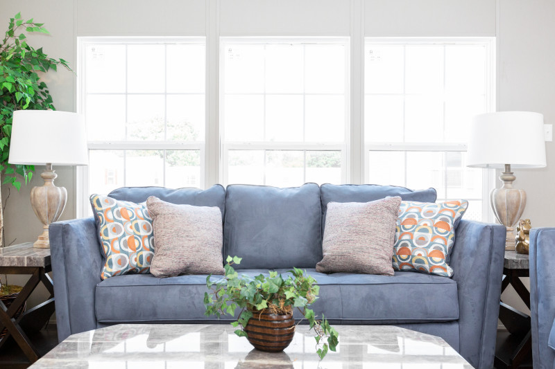 Three large Lux windows and a large blue couch in the living room of a manufactured home.