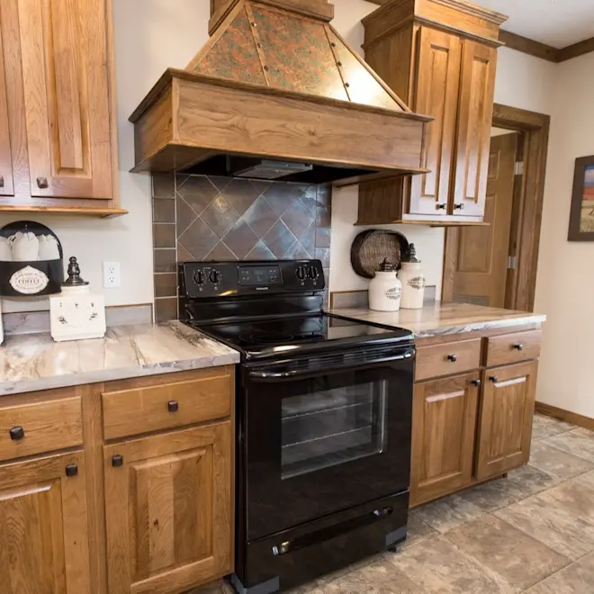 The unique range hood and tile backsplash are show-stopping statement pieces in Frontier kitchen.
