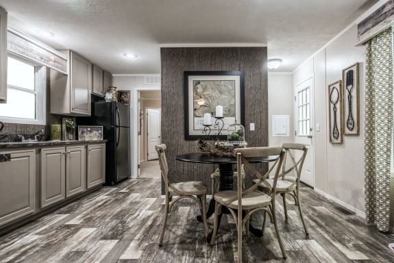 The smaller 6616-711 Pulse is a classic meets modern home with its sleek light cabinets, wood-style floors, dark accent wall in the dining area and open layout. 