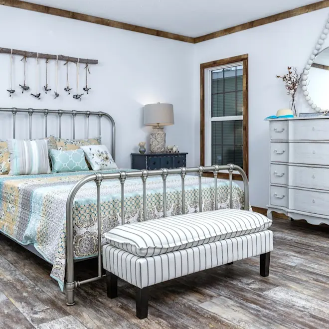 The bedroom in The Liza Jane features weathered wood-style flooring and two large windows.
