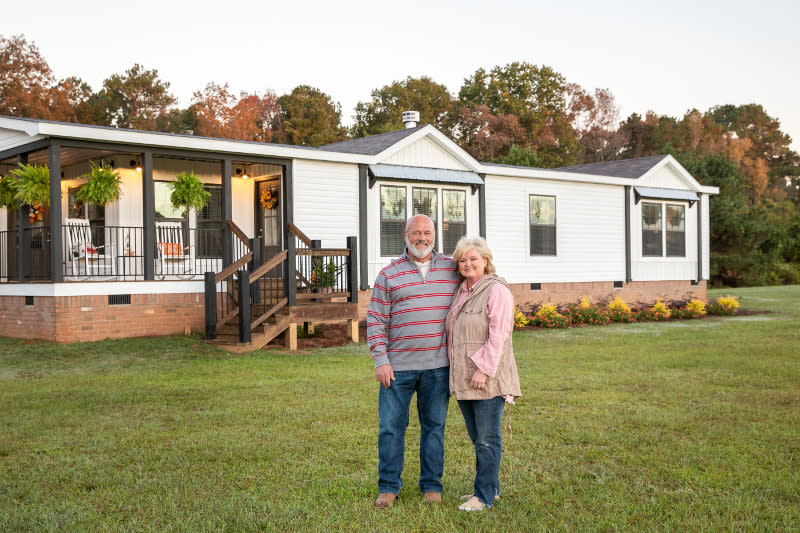 Couple stands in front of their manufactured home that has a farmhouse theme.