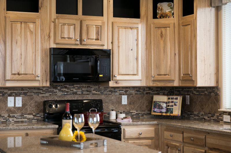 Kitchen of the Spruce by Clayton, with wooden cabinetry and black appliances.