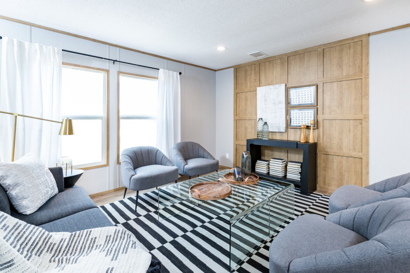 Living room of a Clayton manufactured home with a light wood accent wall, light wood trim, white walls and modern decor.