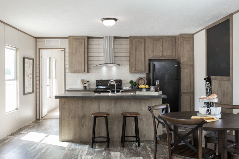 Manufactured home kitchen with cabinets and a large breakfast bar.