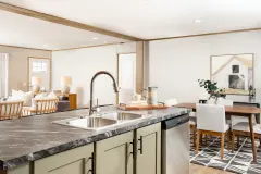 A kitchen island with a double basin sink and sage green cabinets.