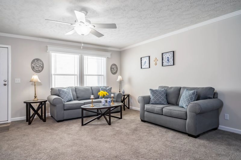 Living room with two gray couches and windows in background.