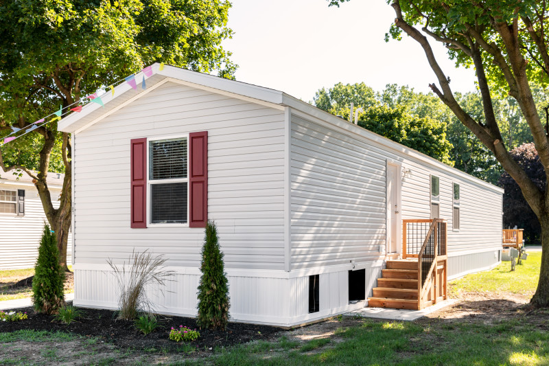 Exterior of single section home with white siding and red shutters.