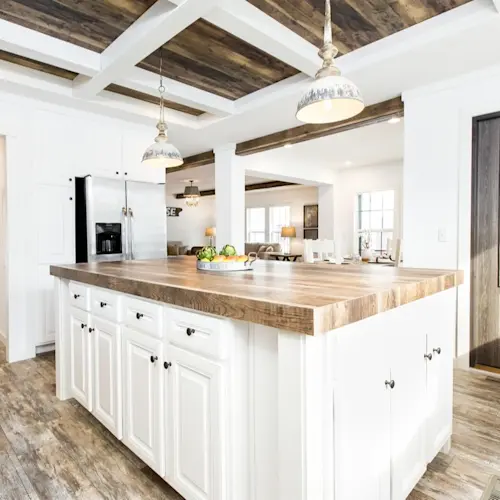 Country style pendant lighting, light gray cabinets and numerous windows create a bright atmosphere in The Lulamae kitchen.