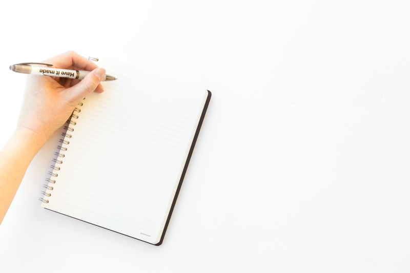 A blank notebook on a white background with a hand about to write something.