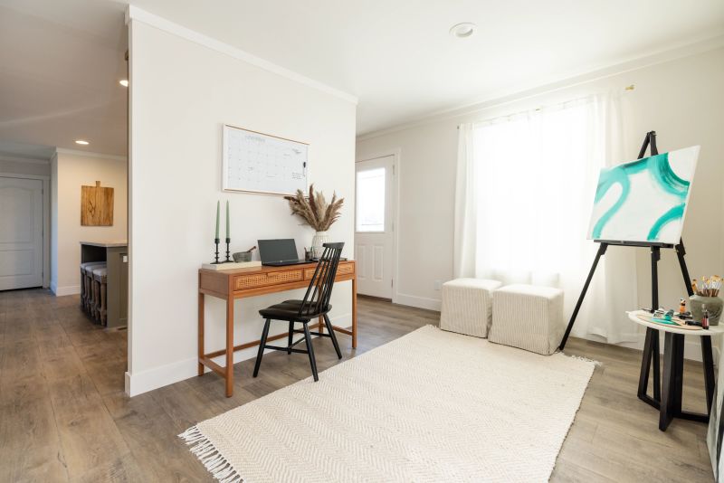 Flex room with white walls that is decorated as an art room. There's a desk and an easel for art set up in the corner.