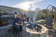 The Woody family roasting marshmallows around their stone firepit