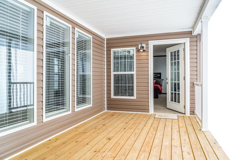 Wooden deck with door ajar leading into bedroom in a Clayton manufactured home.