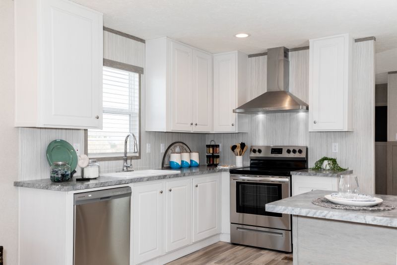 A kitchen is in view with white cabinets, silver appliances, and gray marbled countertops.