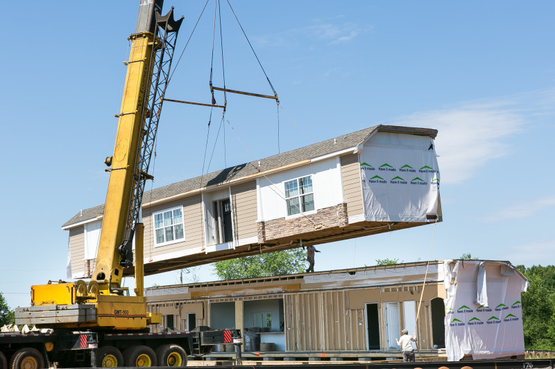 Two modular parts of homes being assembled at a home site.