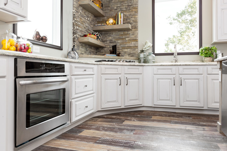 Manufactured home kitchen with white cabinets and stainless-steel appliances.