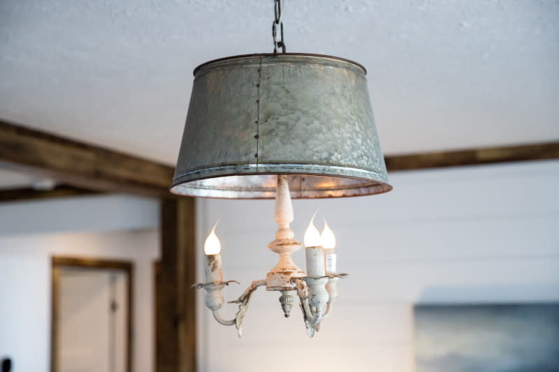 Two round, galvanized metal pendant lights handing from a white ceiling.