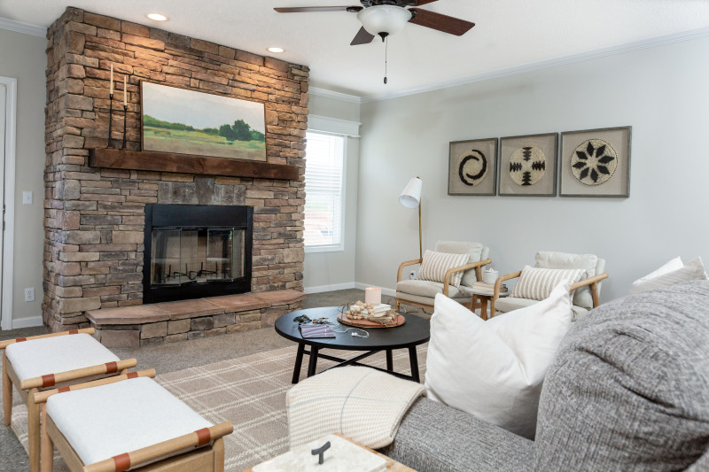 A living room with gray and white furniture and a floor-to-ceiling stone fireplace.