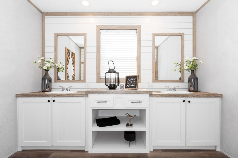 Manufactured home primary bathroom with double vanity and a large window.