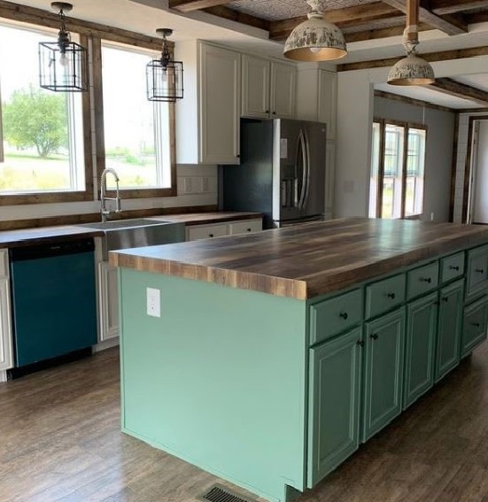 Manufactured home kitchen with white cabinets and a teal island with wooden counters.
