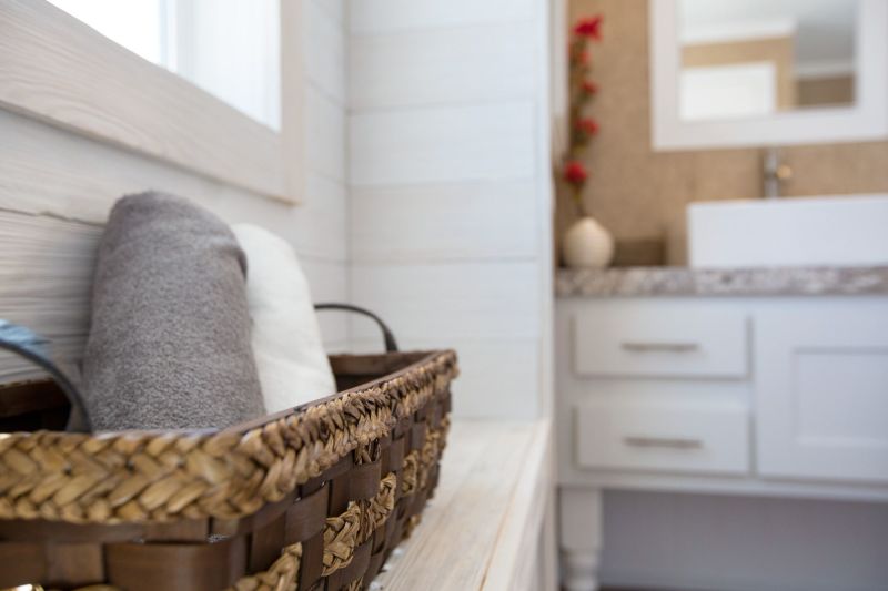 A close-up of a basket with towels on a bench in the bathroom of a manufactured home