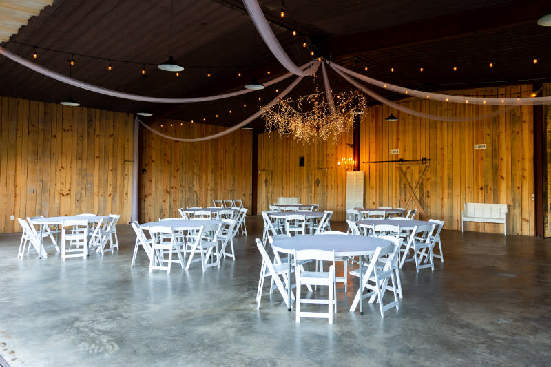 The inside of a wedding venue showcasing white chairs and tables.