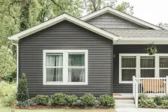 The exterior of a Clayton eBuilt® home with gray siding, windows with white casing and a front porch.