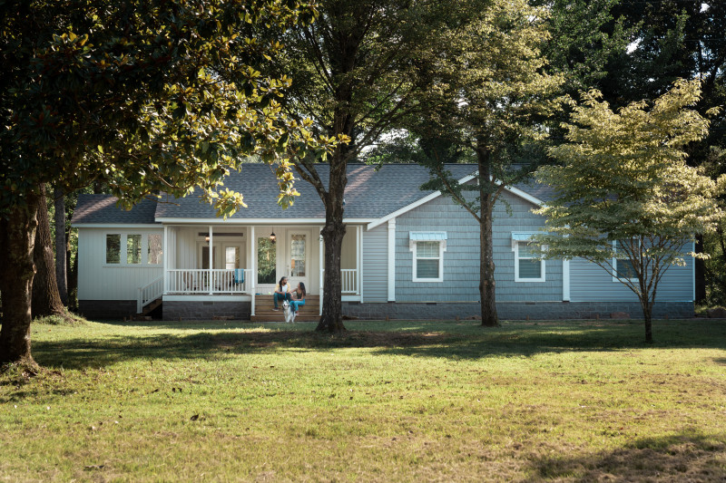 Manufactured home exterior with blue siding and a large front porch.