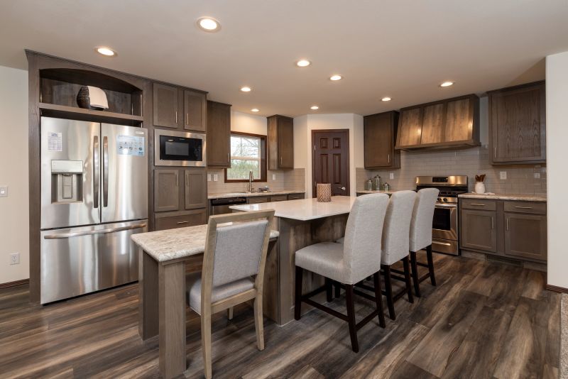 Kitchen with brown cabinetry, stainless steel appliances, and breakfast island with chairs around it.