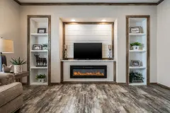 Accent wall in a manufactured home living room with two slender built ins on either side of a recessed focal wall with tv in it and a modern fireplace below.