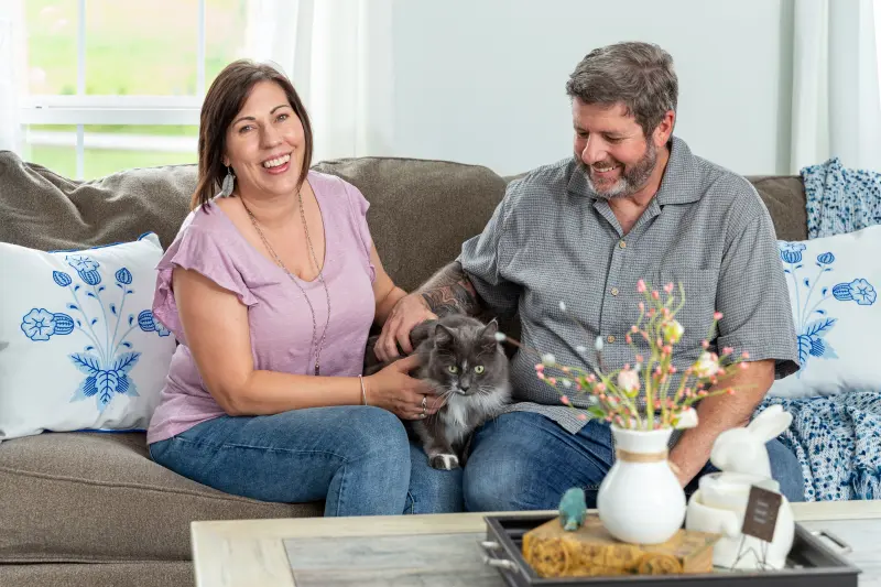 Clayton customers Bonny and Alec sitting on the sofa in their manufactured home with their cat.