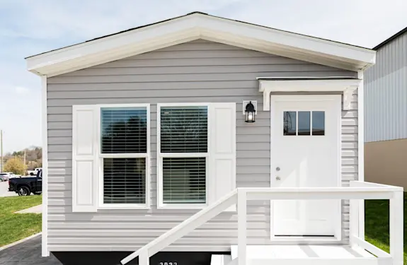 The [model name] features beige vinyl siding and white paneled shutters.
