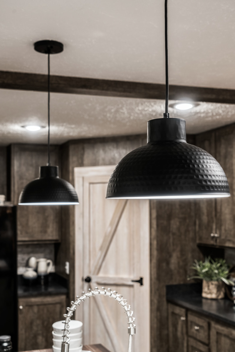 Black, beveled dome light fixtures hang over a kitchen island in farmhouse style home.