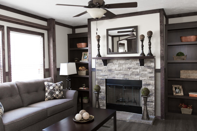 Manufactured home living room with stone fireplace and wooden features.