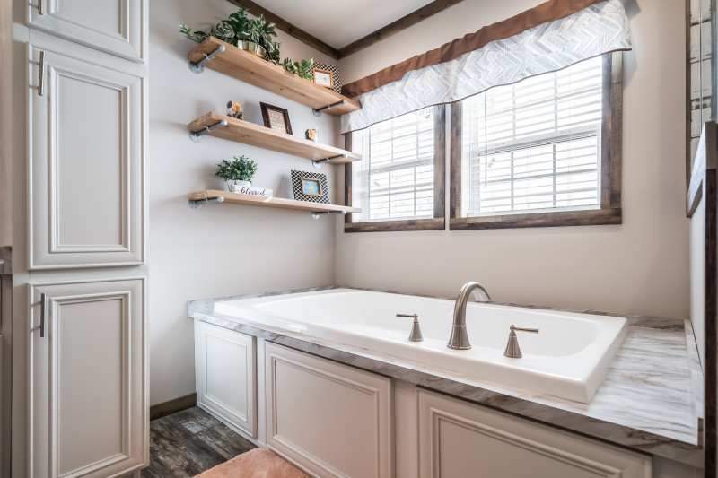 soaking tub, linen closet, and floating open shelves above tub