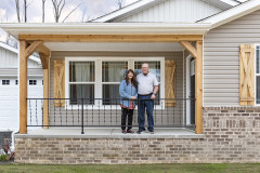 A couple standing on the front porch of their CrossMod home.