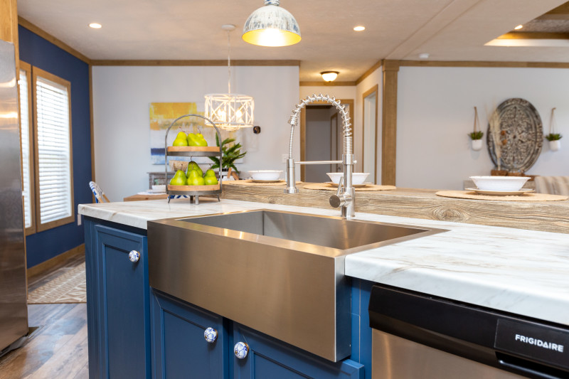 Metal farmhouse sink with apron with gooseneck faucet and blue cabinet base.