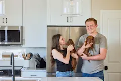 Caidynce and Aidan holding their dachshunds in their kitchen