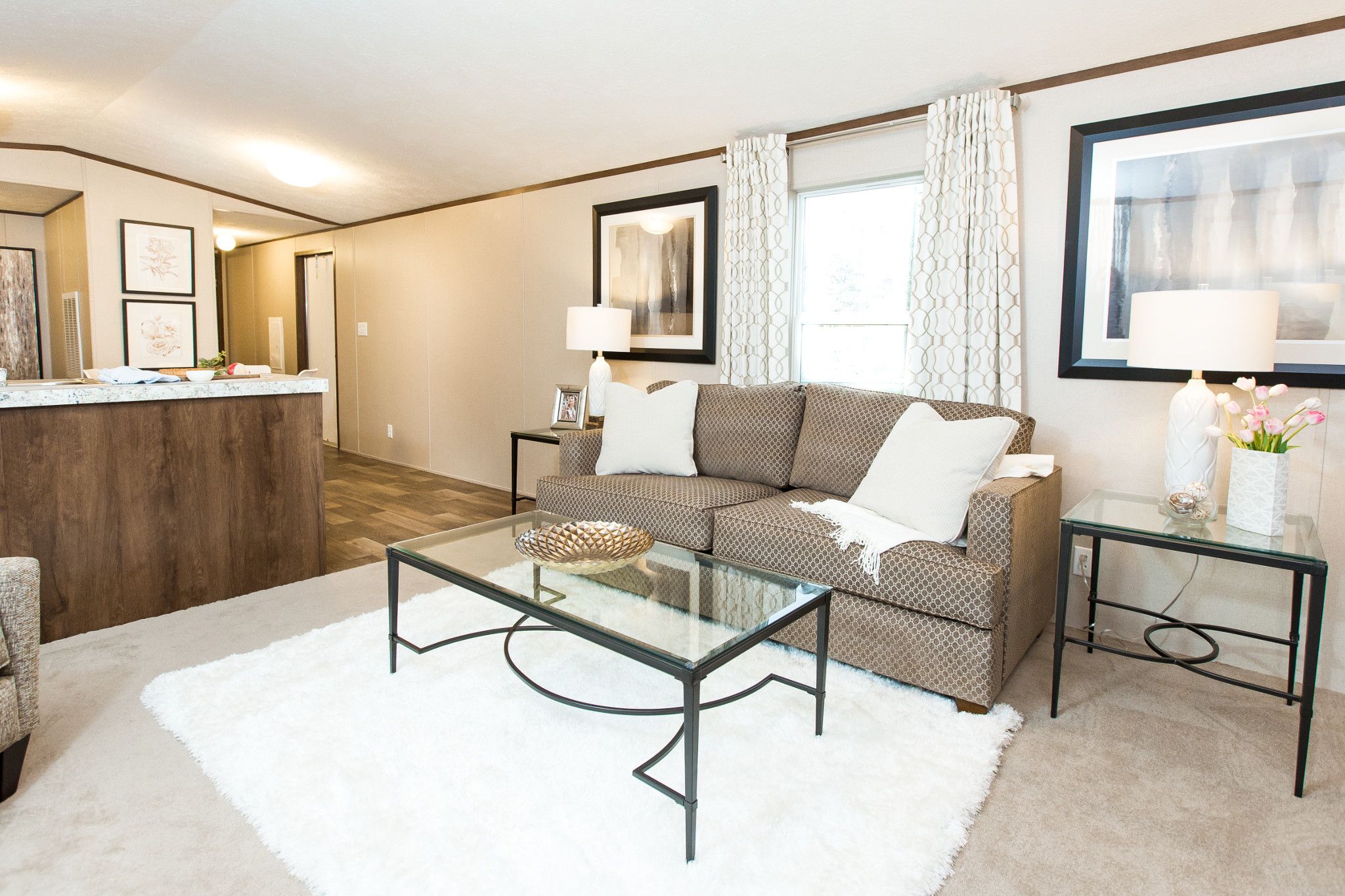 Living room with white walls, white furniture and brown accent tables.