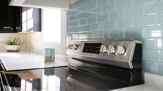 Manufactured home kitchen island with stainless steel stove and turquoise subway tile backsplash