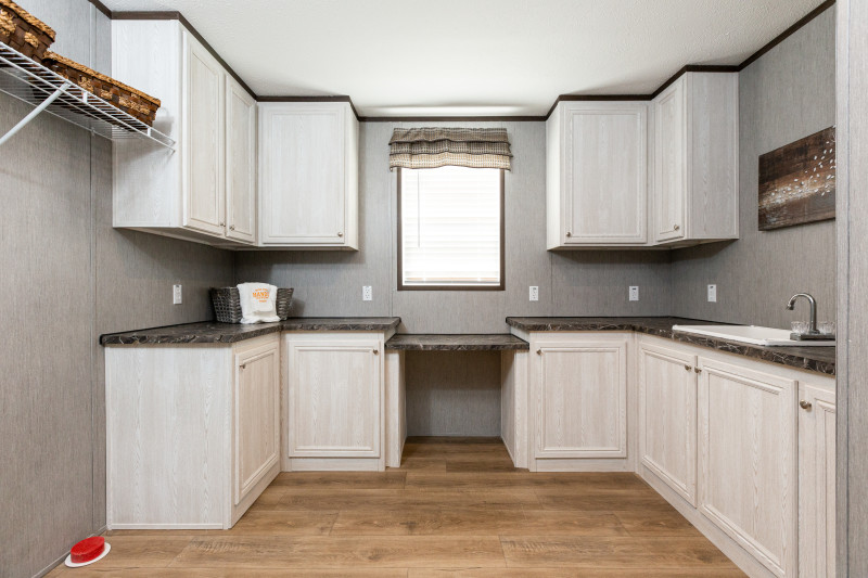 Laundry room and mud room of The Hampton Bay Clayton Built® home featuring lots of cabinet storage and a sink. 