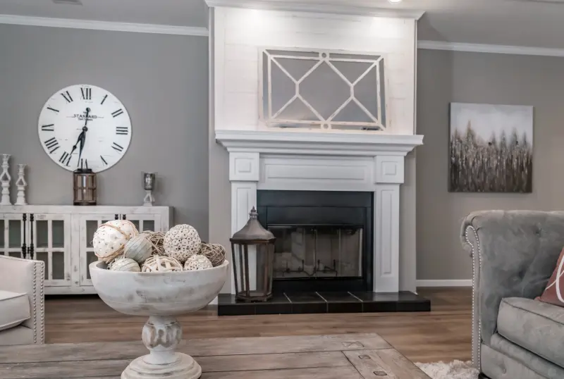 The living room of The Abigail by SouthernEnergy featuring a fireplace with a surrounding white wood mantle and a black stone hearth.
