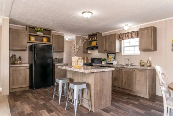 The [model name]'s kitchen features an island with a breakfast bar and open shelving.