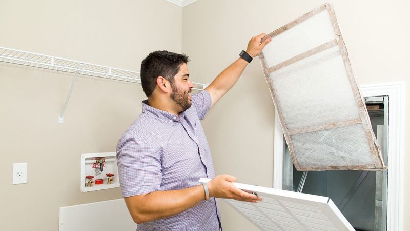 Man with dark hair replacing the air filter in a Clayton Built® home.