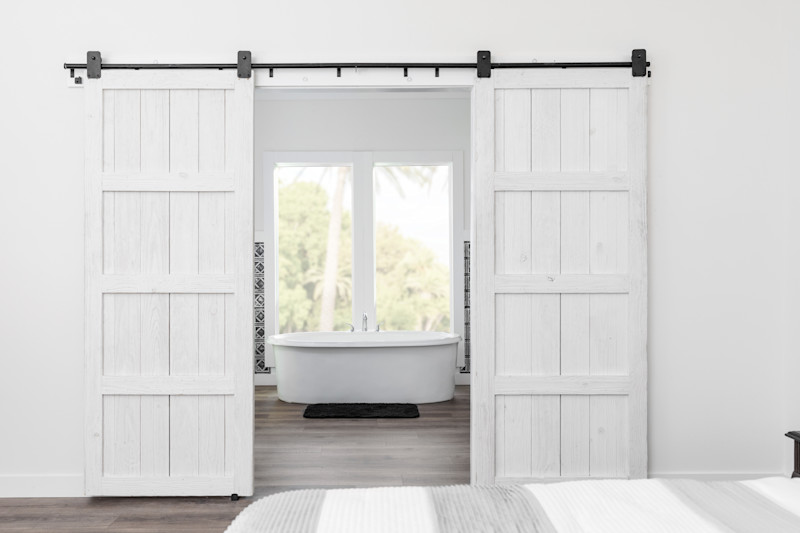 A primary bathroom entryway with white sliding barn doors.