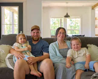 The Isaaks family smiles in their new construction modern manufactured home living room.